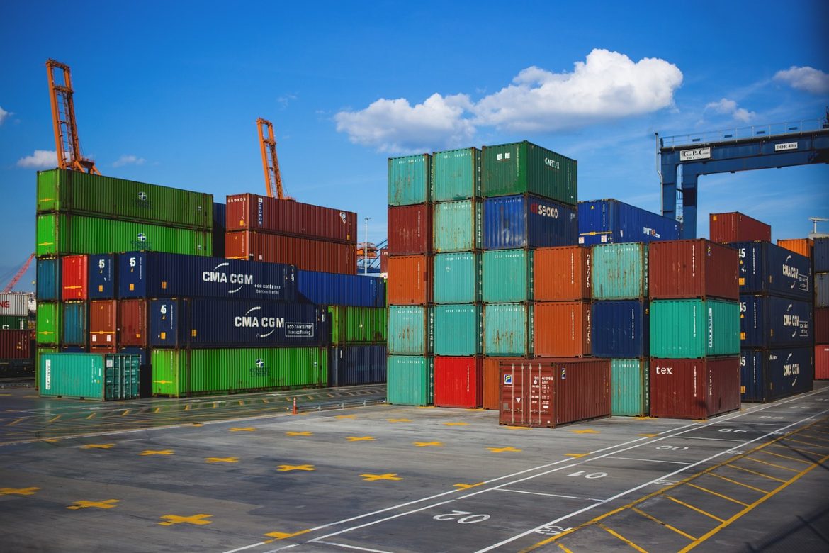 Kolorowe kontenery transportowe ustawione na placu portowym w słoneczny dzień.